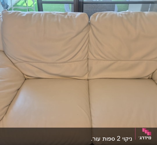 ספה לבנה עם כריות בסלון ליד חלון זכוכית